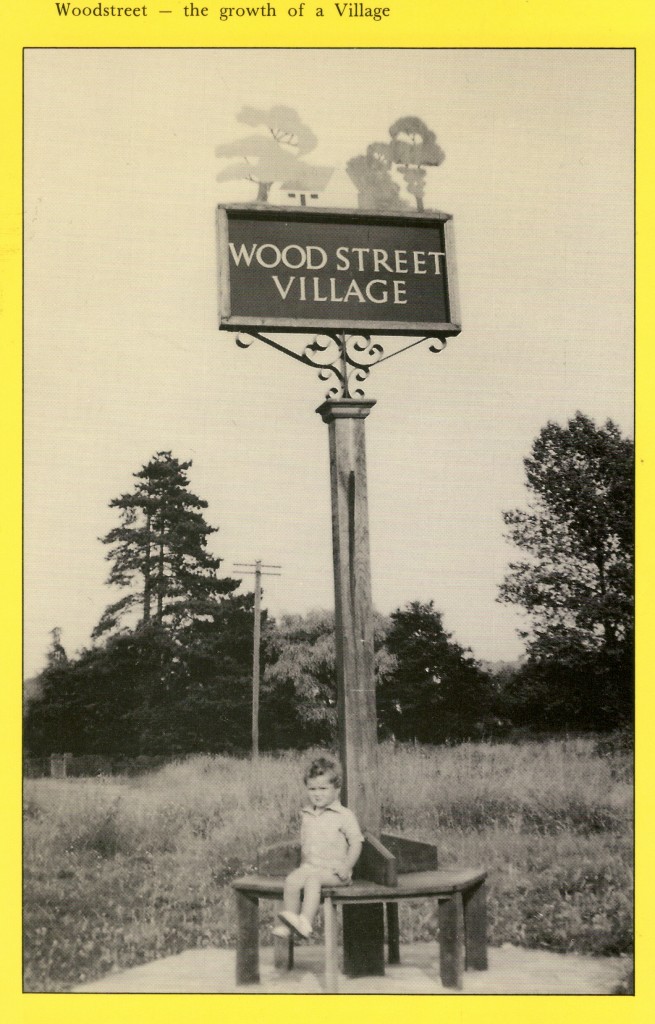 Simon Keen enjoys a seat beneath the newly erected Wood Street Village Sign in 1955